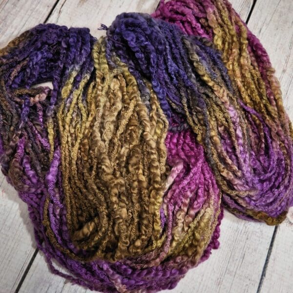 Purple and brown dk yarn on a wooden floor.