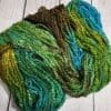 A skein of green and blue yarn on a wooden table.
