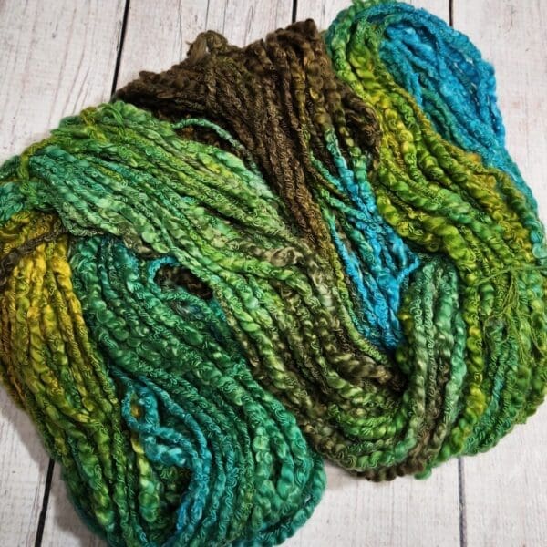 A skein of green and blue yarn on a wooden table.