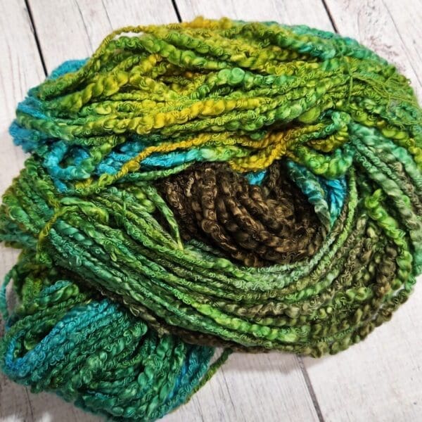 A skein of green and blue yarn on a wooden table.