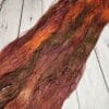 A skein of brown and orange yarn on a wooden floor.
