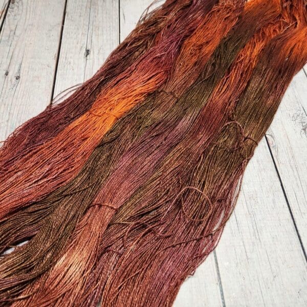 A skein of brown and orange yarn on a wooden floor.
