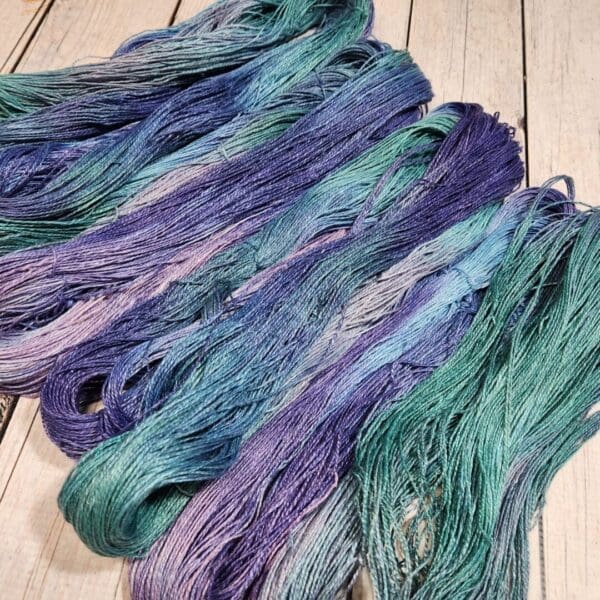 Skeins of purple, blue and green yarn on a wooden table.