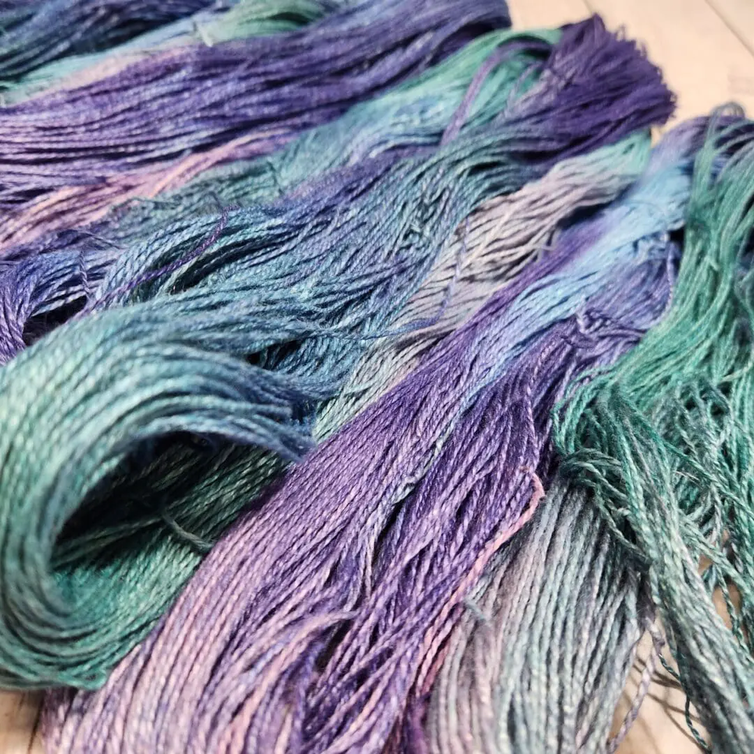 A skein of purple and blue yarn on a wooden table.