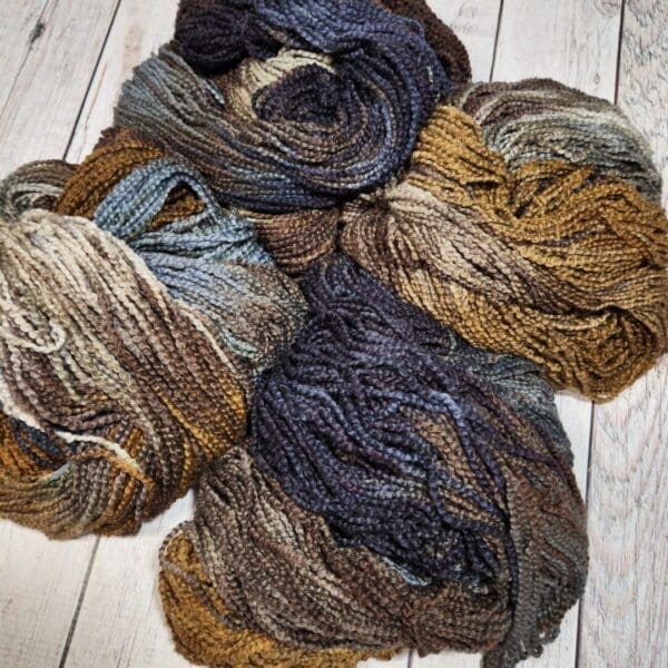 Four skeins of yarn on a wooden floor.