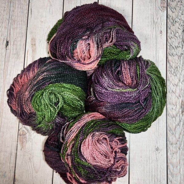 Four balls of yarn on a wooden floor.