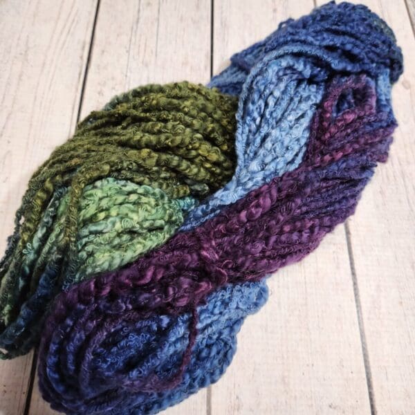 A skein of yarn with blue, green, and purple colors.