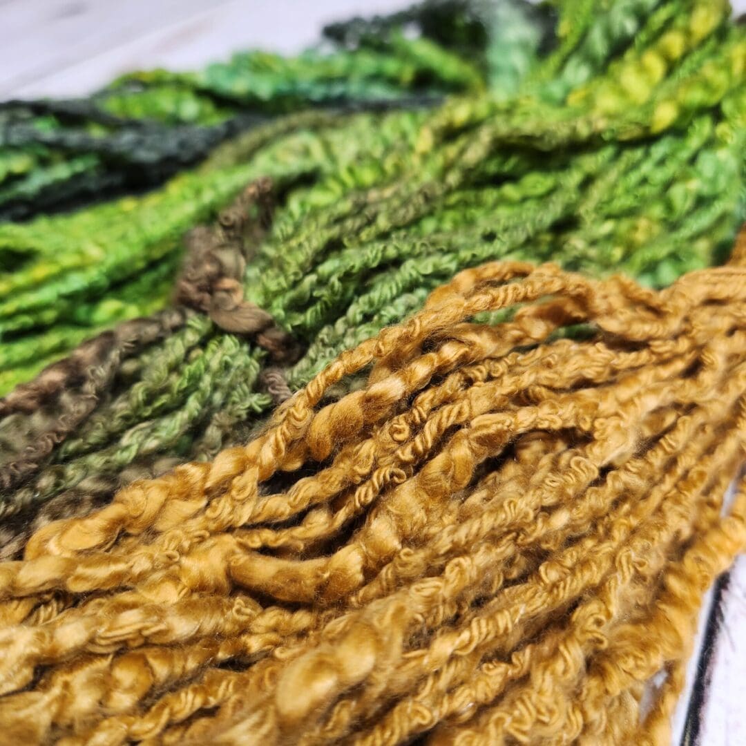 A bunch of green and yellow yarns on a table.