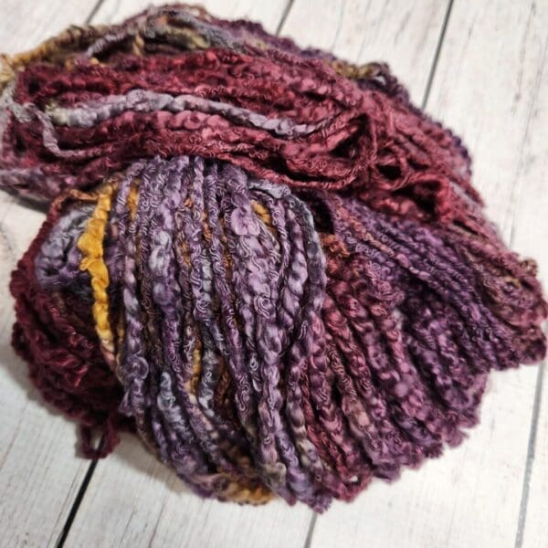 A skein of purple and yellow yarn on a wooden table.