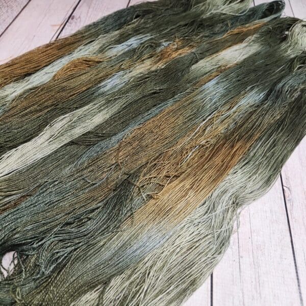 A skein of green and brown yarn on a wooden floor.