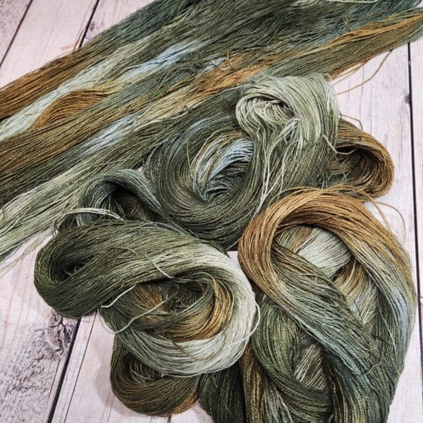 Two skeins of green and brown yarn on a wooden table.