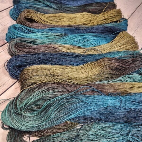 A bunch of skeins of blue, green, and brown yarn.