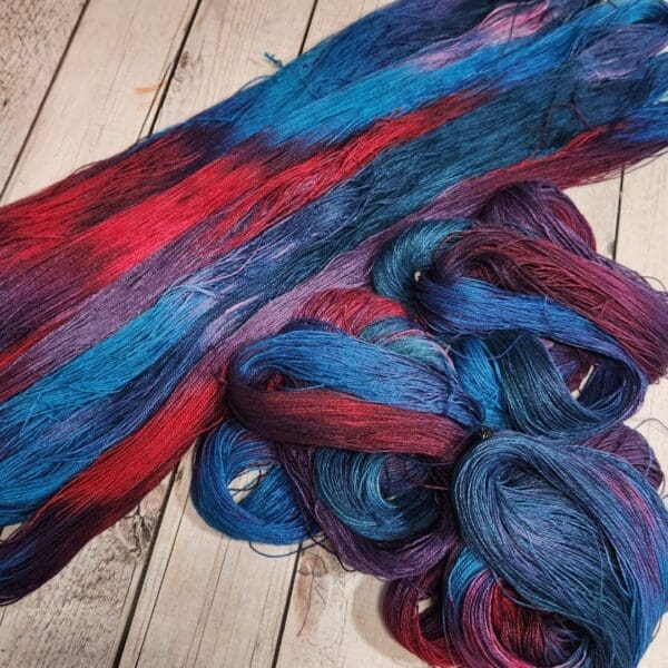 Two skeins of blue and red yarn on a wooden table.