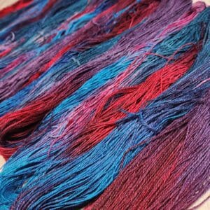 Skeins of blue, red, and purple yarn on a table.
