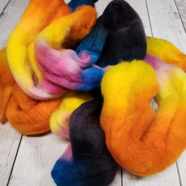 A pile of colorful roving on a wooden table.