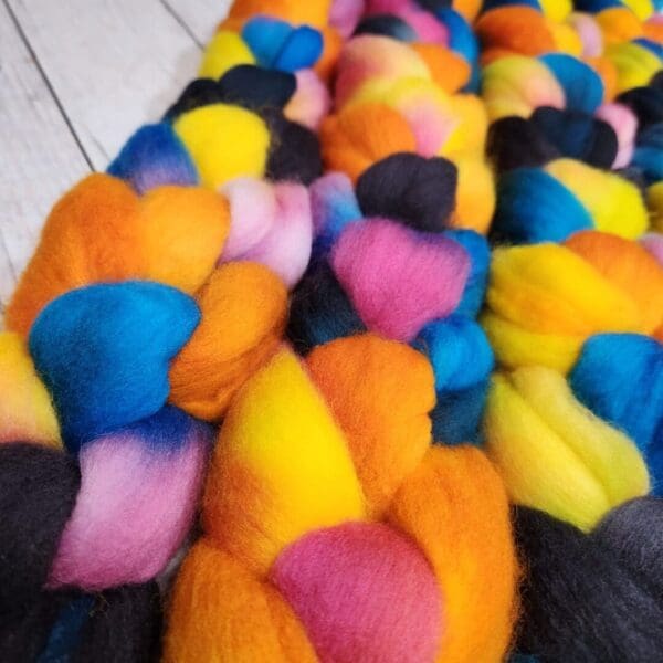 A pile of colorful roving on a wooden table.