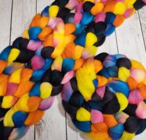 A colorful skein of roving on a wooden table.