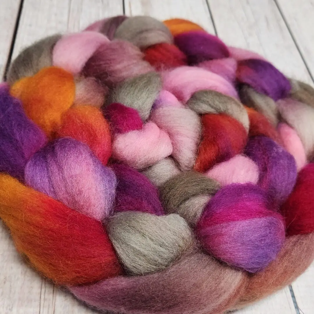 A skein of colorful wool roving on a wooden table.