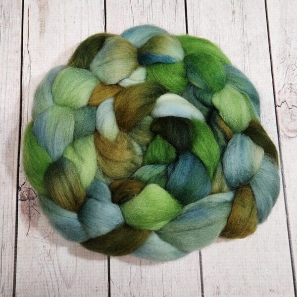 A green and blue roving on top of a wooden table.