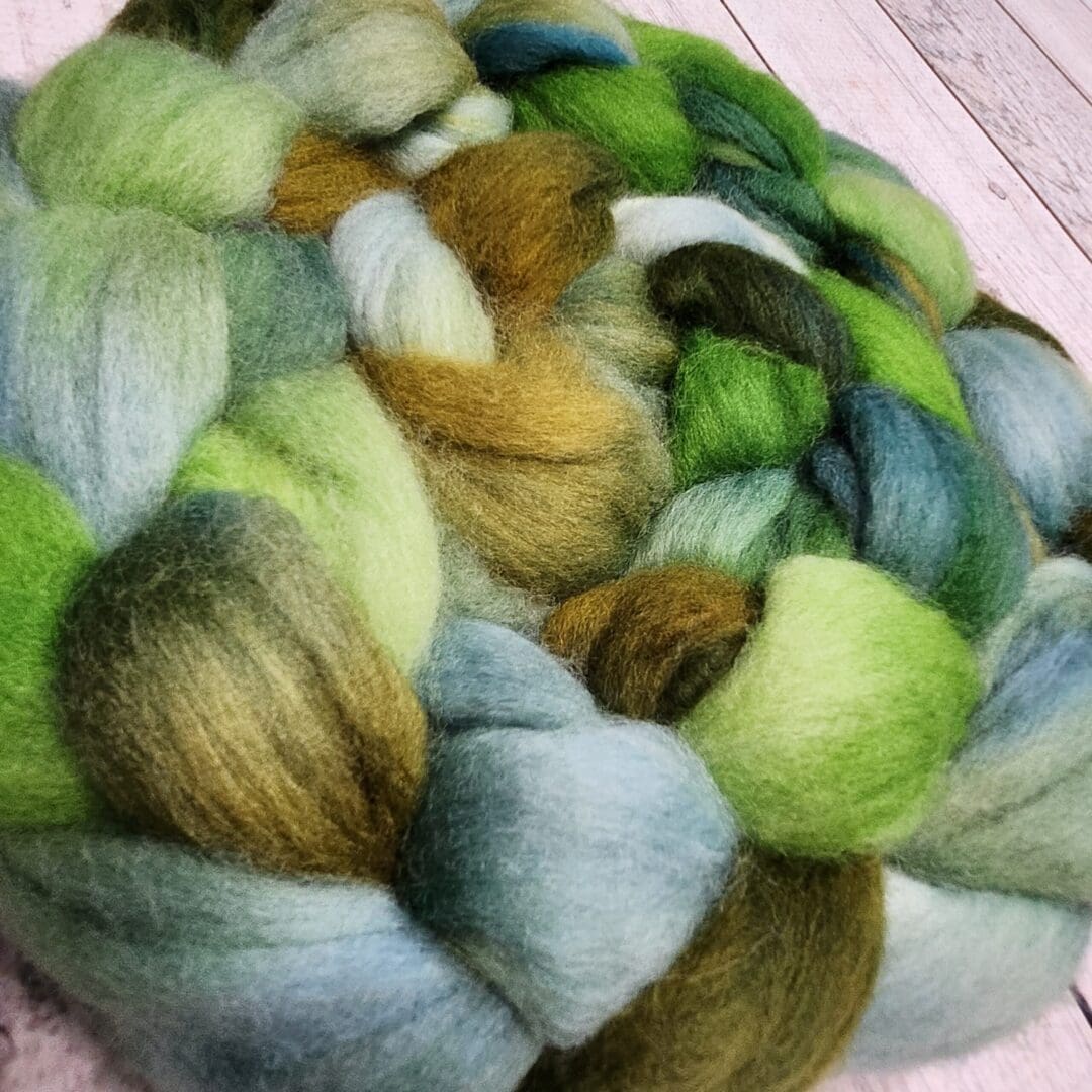 A skein of green and blue wool roving.