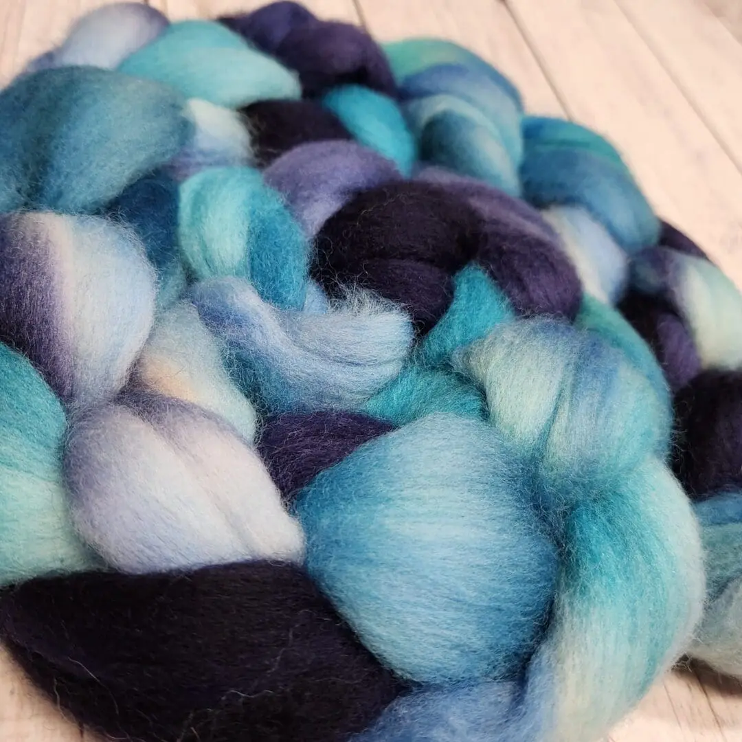 A skein of blue and black wool roving.