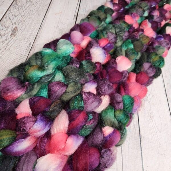 Purple and green roving on a wooden table.