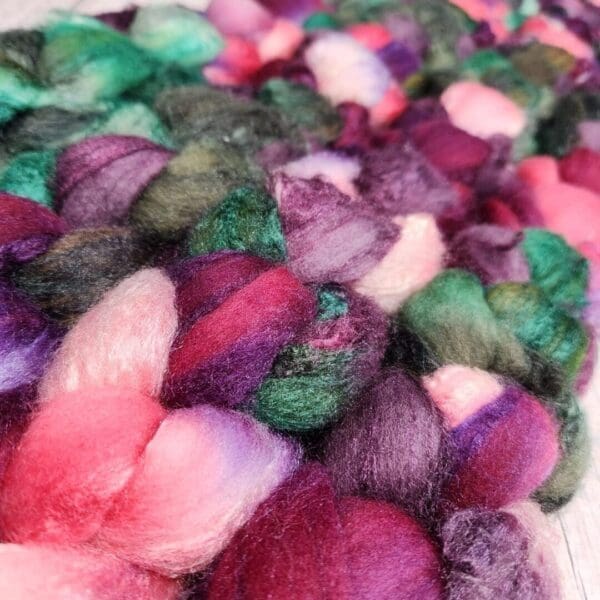 A close up of a purple, green, and pink roving.