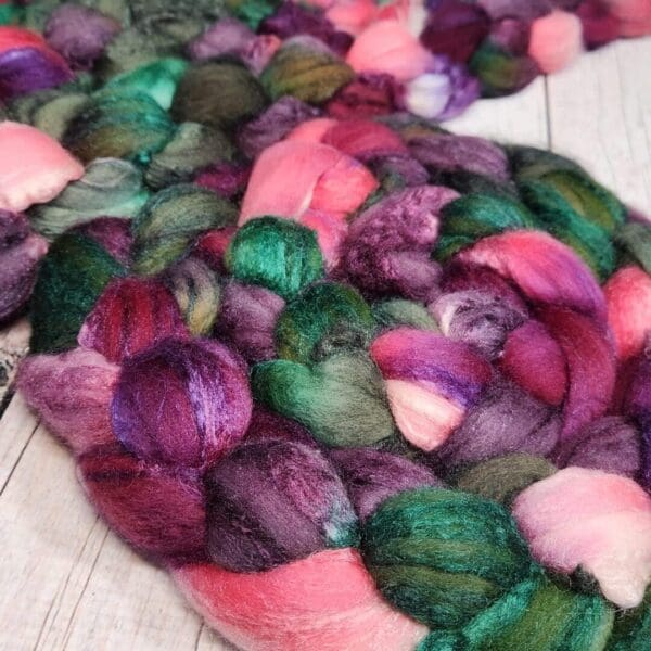 A pile of purple and green fibers on a wooden table.