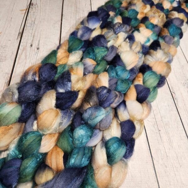 A pile of blue, green, and yellow roving.