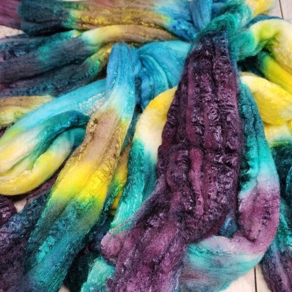 A pile of dyed roving on a wooden surface.