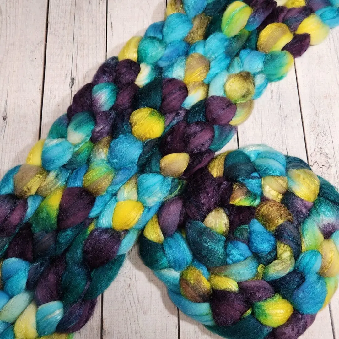 A blue, yellow, and green roving laying on top of a wooden table.