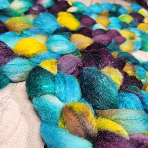 Purple, blue and yellow roving on a wooden table.