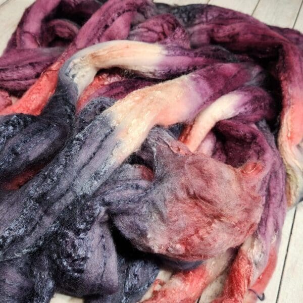 Purple and pink roving on a wooden floor.