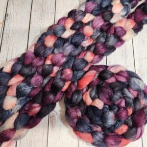 A skein of purple, pink, and black roving.