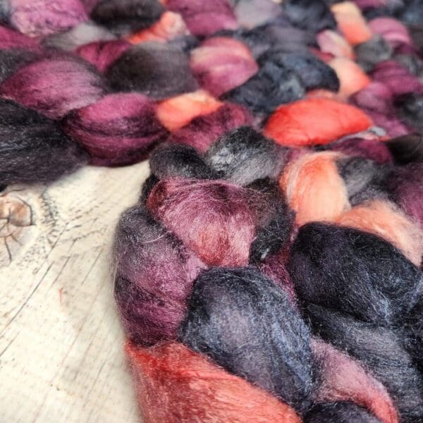 Purple and black wool roving on top of a wooden table.