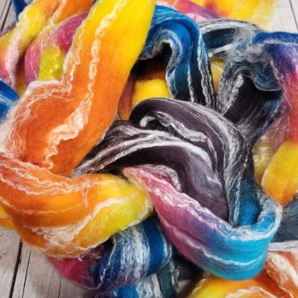 A pile of colorful wool roving on top of a wooden table.