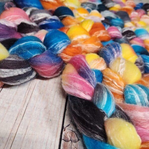 A colorful skein of roving on top of a wooden table.