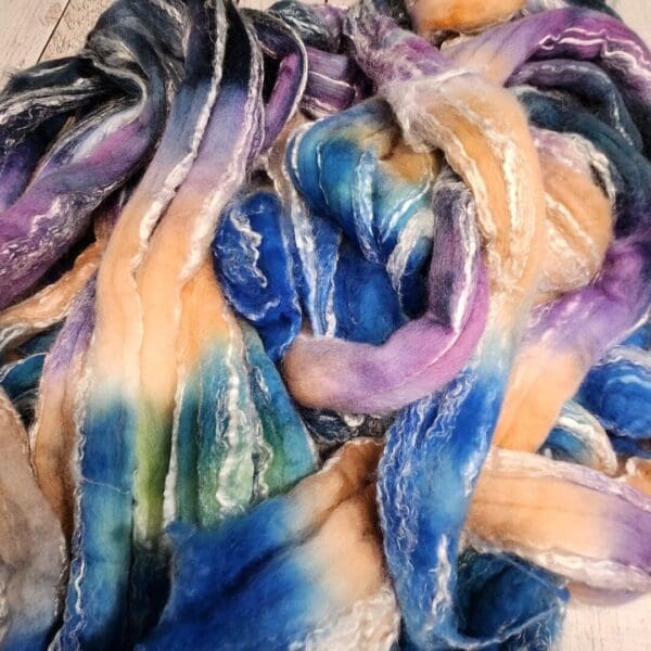 A pile of dyed roving on a wooden floor.