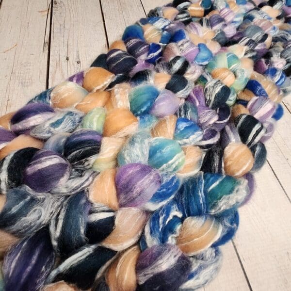 A pile of colorful yarn on a wooden floor.