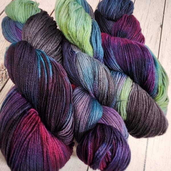 Purple, green, and blue skeins on a wooden table.