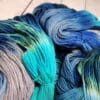 Skeins of blue and grey yarn on a wooden table.