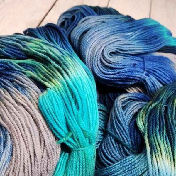 Skeins of blue and grey yarn on a wooden table.