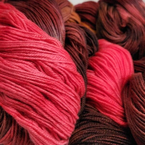 Skeins of red and brown yarn on a white surface.
