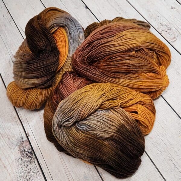 Three skeins of yarn on a wooden floor.