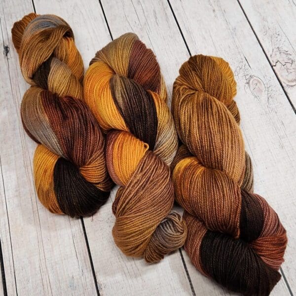 Three skeins of yarn in brown, orange and black.