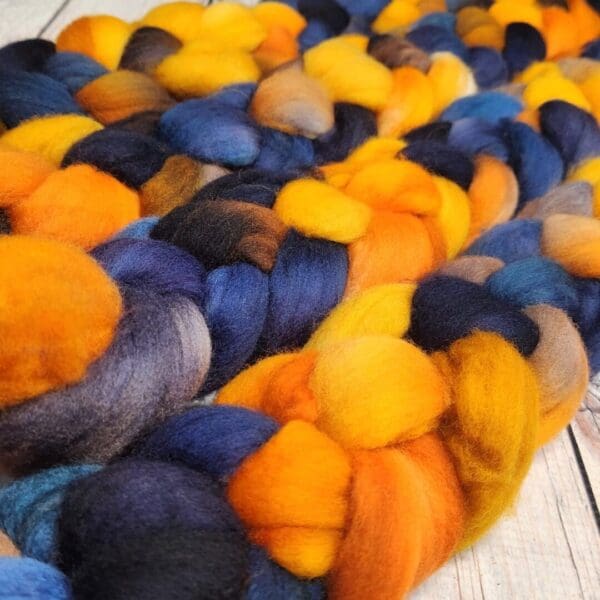 A bunch of orange, blue and black roving on a wooden table.