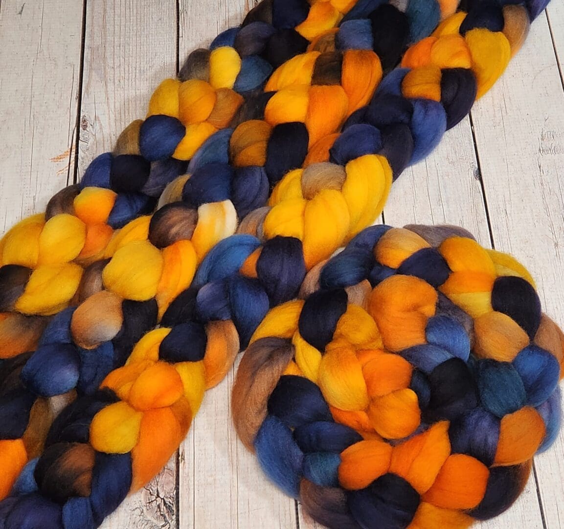 A blue, yellow and orange roving on a wooden table.