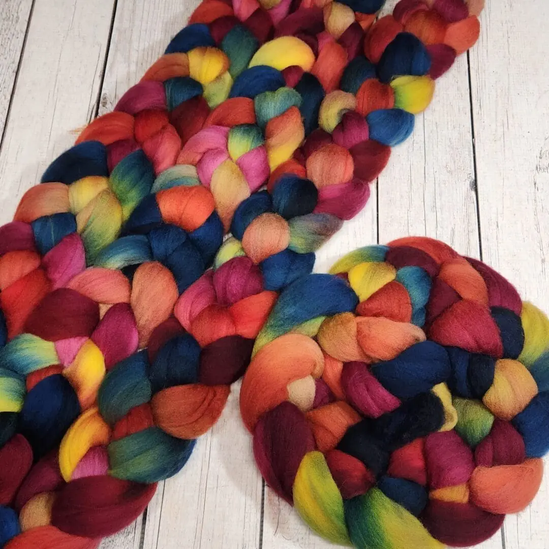 A colorful skein of roving on a wooden table.
