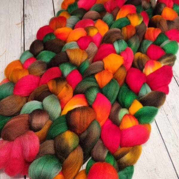 A pile of colorful roving on a wooden floor.