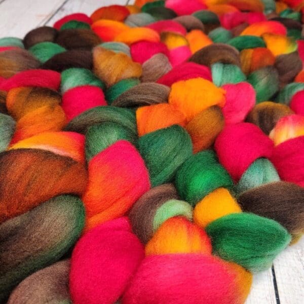 A pile of colorful wool roving on a wooden table.